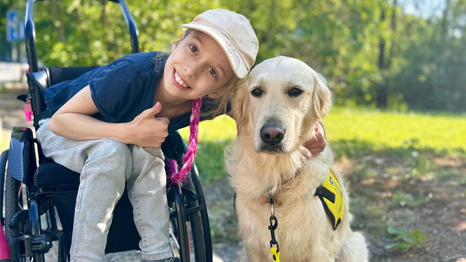 holčička na vozíčku se usmívá s asistenčním psem helppes