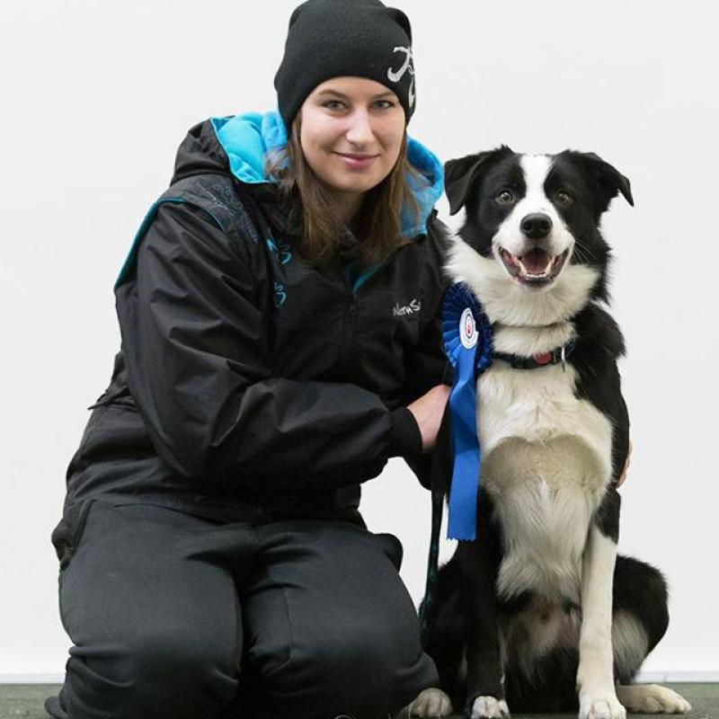 usměvavá žena sedí vedle svého psa, ktetý právě vyhrál medaily v dogdancingu