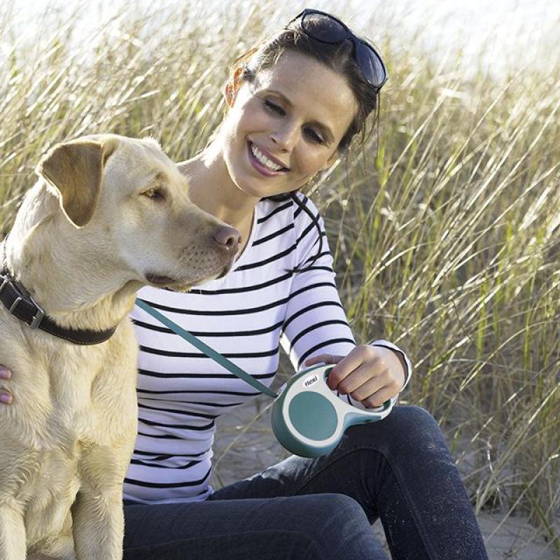 žena se usmívá na svého psa a drží v ruce flexi vodítko
